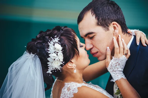 Casal jovem beijando no vestido de casamento. Noiva segurando buquê de flores — Fotografia de Stock