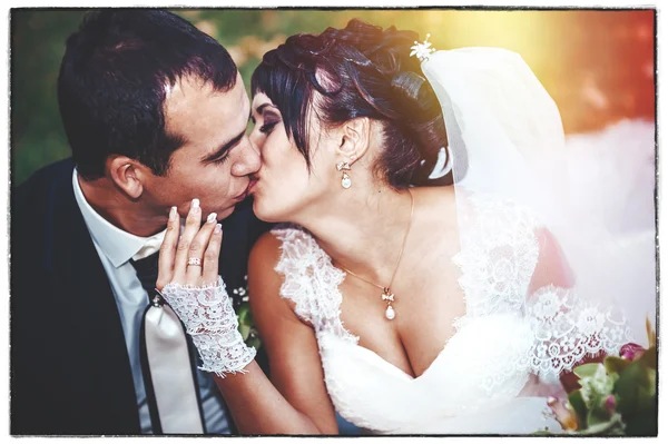 Jeune couple embrassant en robe de mariée. Mariée tenant bouquet de fleurs — Photo