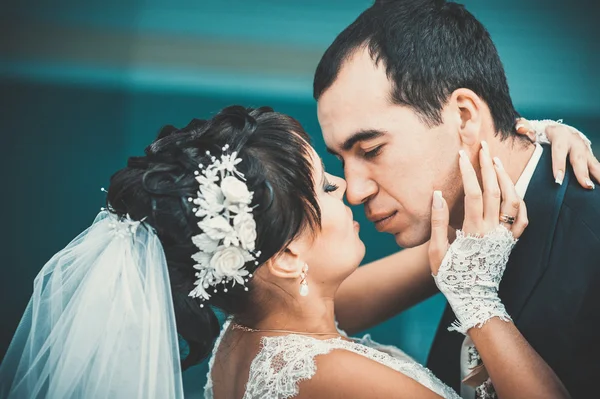 Giovane coppia che si bacia in abito da sposa. Sposa che tiene mazzo di fiori — Foto Stock