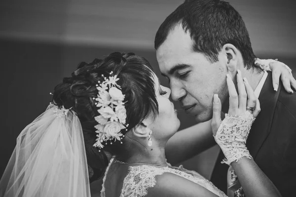 Young couple kissing in wedding gown. Bride holding bouquet of flowers — Stock Photo, Image