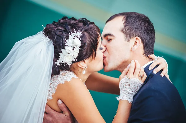 Young couple kissing in wedding gown. Bride holding bouquet of flowers — Stock Photo, Image