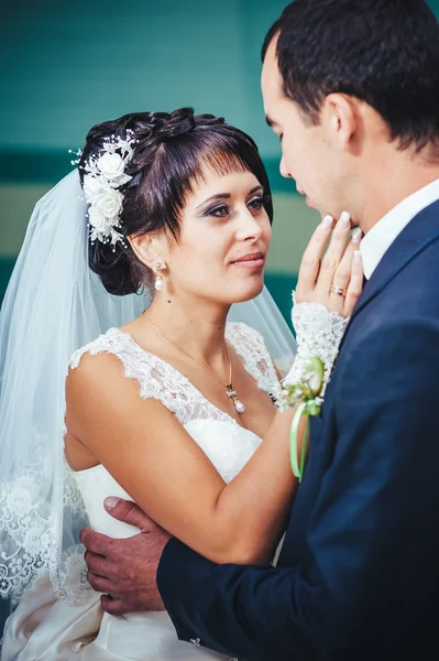 Casal jovem beijando no vestido de casamento. Noiva segurando buquê de flores — Fotografia de Stock