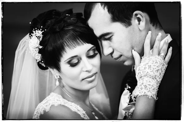 Casal jovem beijando no vestido de casamento. Noiva segurando buquê de flores — Fotografia de Stock