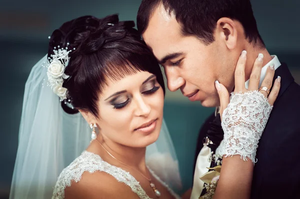 Young couple kissing in wedding gown. Bride holding bouquet of flowers — Stock Photo, Image