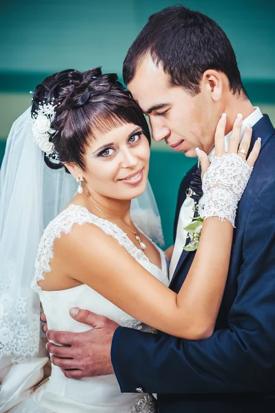 Young couple kissing in wedding gown. Bride holding bouquet of flowers — Stock Photo, Image