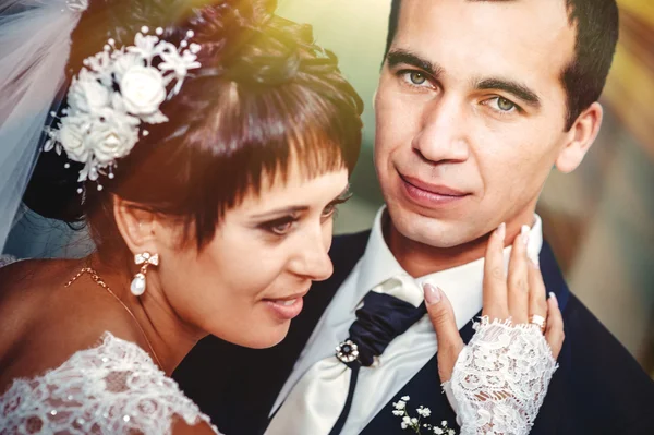 Young couple kissing in wedding gown. Bride holding bouquet of flowers — Stock Photo, Image