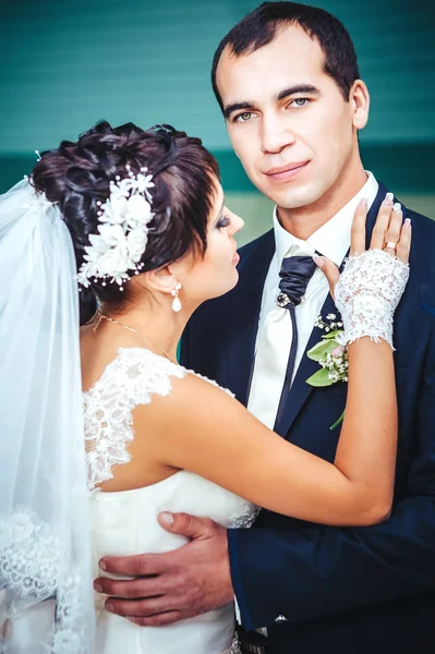 Young couple kissing in wedding gown. Bride holding bouquet of flowers — Stock Photo, Image