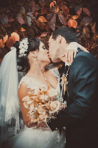 Fiatal pár csók az esküvői ruha. menyasszony gazdaság csokor virág — Stock Fotó