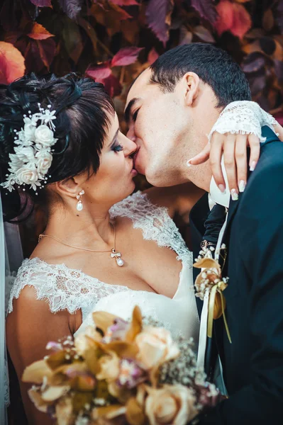 Casal jovem beijando no vestido de casamento. Noiva segurando buquê de flores — Fotografia de Stock