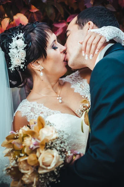 Casal jovem beijando no vestido de casamento. Noiva segurando buquê de flores — Fotografia de Stock