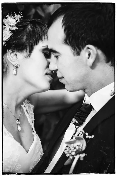 Casal jovem beijando no vestido de casamento. Noiva segurando buquê de flores — Fotografia de Stock