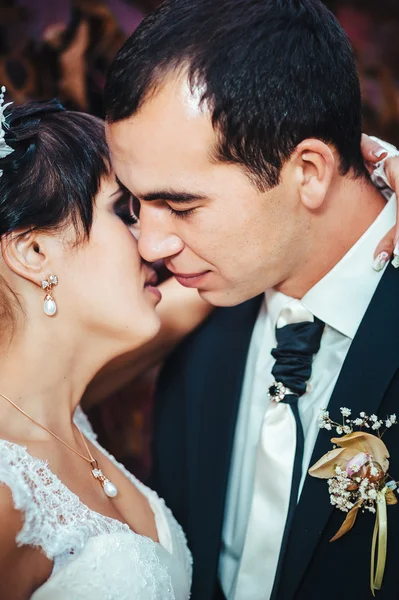 Young couple kissing in wedding gown. Bride holding bouquet of flowers — Stock Photo, Image