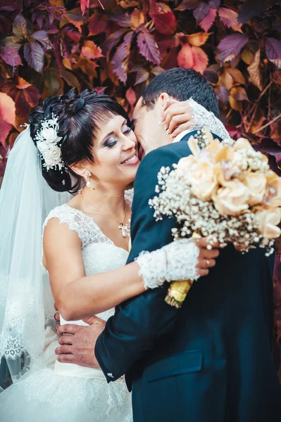 Casal jovem beijando no vestido de casamento. Noiva segurando buquê de flores — Fotografia de Stock