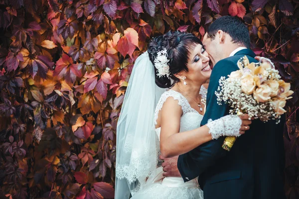 Casal jovem beijando no vestido de casamento. Noiva segurando buquê de flores — Fotografia de Stock