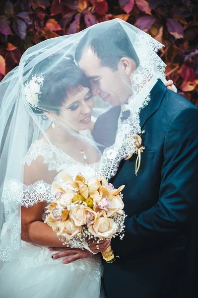 Casal jovem beijando no vestido de casamento. Noiva segurando buquê de flores — Fotografia de Stock