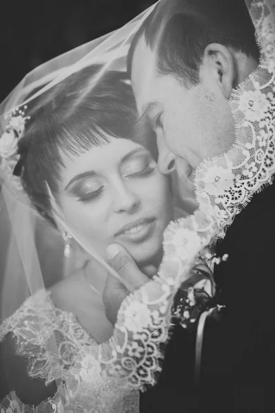Jeune couple embrassant en robe de mariée. Mariée tenant bouquet de fleurs — Photo