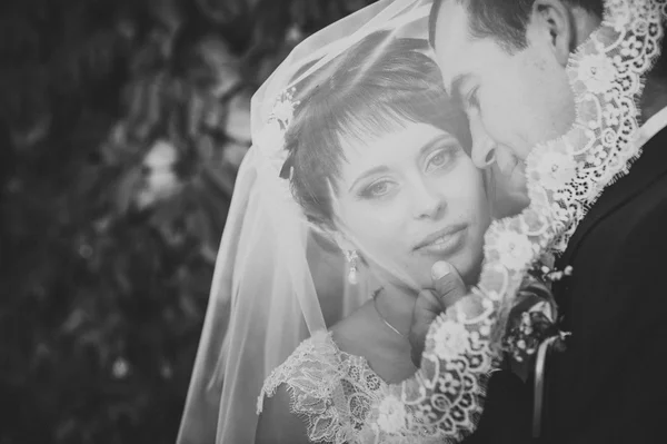 Jeune couple embrassant en robe de mariée. Mariée tenant bouquet de fleurs — Photo