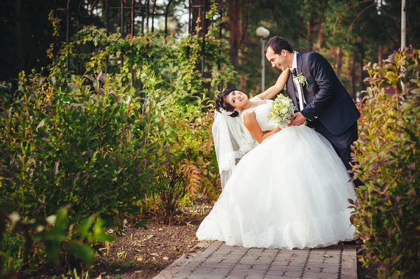 接吻的结婚礼服的年轻夫妇。新娘控股束鲜花 — 图库照片