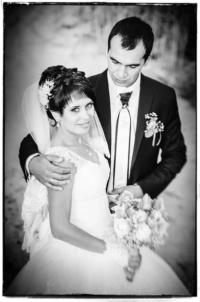 Jeune couple embrassant en robe de mariée. Mariée tenant bouquet de fleurs — Photo