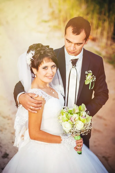 Junges Paar küsst sich im Brautkleid. Braut mit Blumenstrauß — Stockfoto