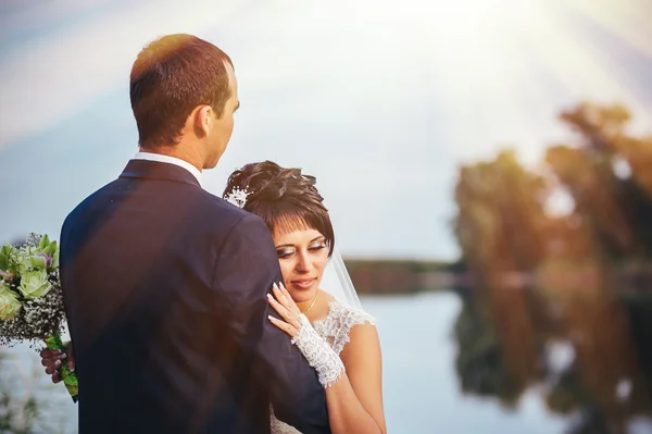 Casal jovem beijando no vestido de casamento. Noiva segurando buquê de flores — Fotografia de Stock