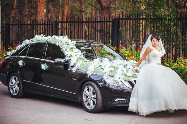 De bruid in de buurt van een zwart bruiloft auto — Stockfoto