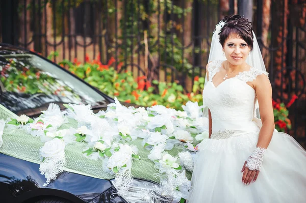Bruden nära en svart bröllop bil — Stockfoto