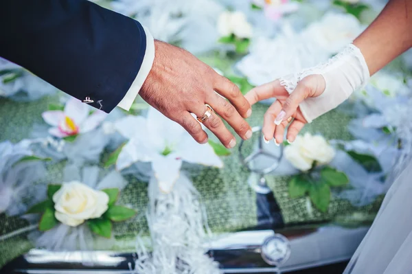 Mains de la mariée et le marié. bouquet de mariage sur voiture noire — Photo