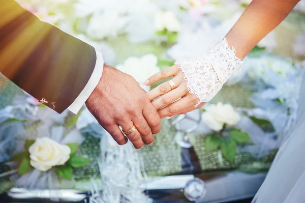 Le mani degli sposi. bouquet da sposa su auto nera — Foto Stock