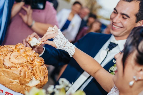 Groom holding slice of traditional wedding round loaf and bride salt it. — Stock Photo, Image
