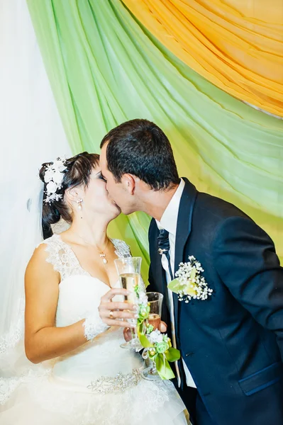 Encantadora novia con novio abraza y besos en su celebración de la boda en un restaurante de lujo. ramo de flores, vestido de novia. pareja recién casada enlujo moderno hotel hall —  Fotos de Stock