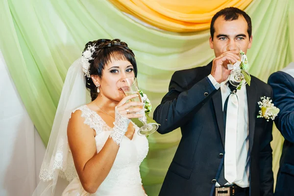 Charming bride with groom embraces and kisses on their wedding celebration in luxurious restaurant. bouquet of flowers, bridal dress. newly married couple atluxury modern hotel hall — Stock Photo, Image