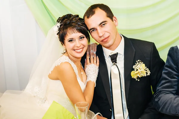 Γοητευτική νύφη με γαμπρός αγκαλιάζει και φιλιά στην γιορτή τους γάμο στο πολυτελές εστιατόριο. μπουκέτο λουλούδια, νυφικό φόρεμα. το μοντέρνο ξενοδοχείο αίθουσα νιόπαντρο ζευγάρι atluxury — Φωτογραφία Αρχείου
