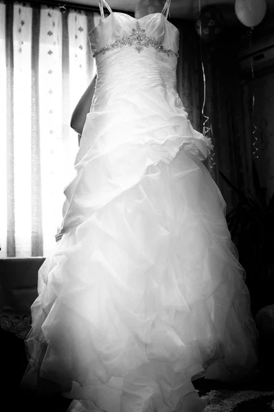 Hochzeitskleid, das an einer Schulter hängt. Hochzeitskleid hängt am Fenster — Stockfoto