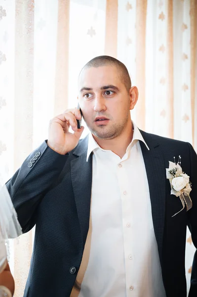 Retrato de belo jovem noivo de terno e gravata branca falando ao telefone — Fotografia de Stock