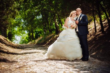 Gelin ve damat, düğün günü açık havada yürüyüş Doğa bahar. mutlu yeni evli kadın ve erkek yeşil park kucaklayan gelin çift. sevgi dolu evlilik çift açık.