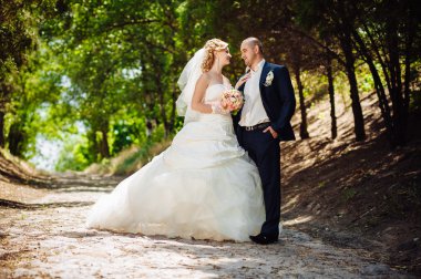 Gelin ve damat, düğün günü açık havada yürüyüş Doğa bahar. mutlu yeni evli kadın ve erkek yeşil park kucaklayan gelin çift. sevgi dolu evlilik çift açık.