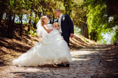 Gelin ve damat, düğün günü açık havada yürüyüş Doğa bahar. mutlu yeni evli kadın ve erkek yeşil park kucaklayan gelin çift. sevgi dolu evlilik çift açık.