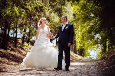 Gelin ve damat, düğün günü açık havada yürüyüş Doğa bahar. mutlu yeni evli kadın ve erkek yeşil park kucaklayan gelin çift. sevgi dolu evlilik çift açık.