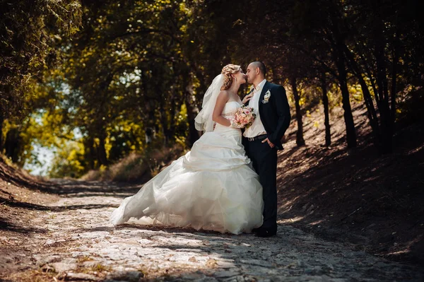 Brudparet på bröllopsdagen promenader utomhus på vår natur. Brudparet, lycklig nygift kvinna och man som omfattar i grön park. kärleksfull bröllop par utomhus. — Stockfoto