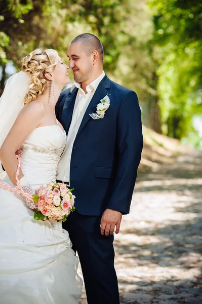 Novia y novio en el día de la boda caminando al aire libre en la naturaleza de primavera. Pareja nupcial, feliz mujer recién casada y hombre abrazándose en el parque verde. Amar pareja de boda al aire libre . — Foto de Stock