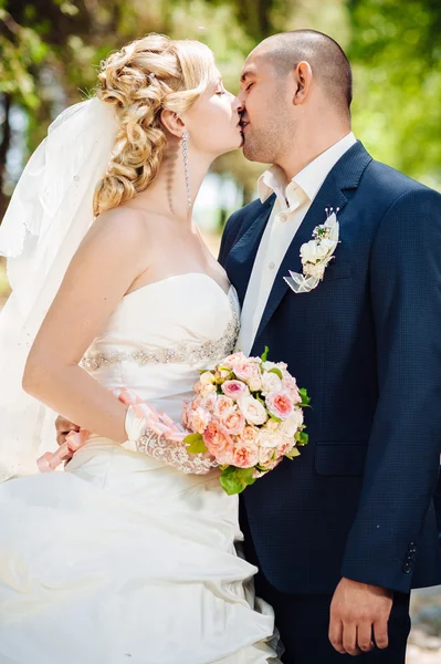 Novia y novio en el día de la boda caminando al aire libre en la naturaleza de primavera. Pareja nupcial, feliz mujer recién casada y hombre abrazándose en el parque verde. Amar pareja de boda al aire libre . — Foto de Stock