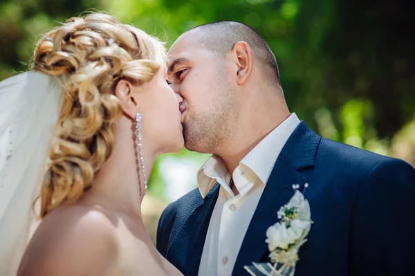 Noiva e noivo no dia do casamento andando ao ar livre na natureza de primavera. Casal nupcial, mulher recém-casada feliz e homem abraçando no parque verde. Casal de amor ao ar livre . — Fotografia de Stock