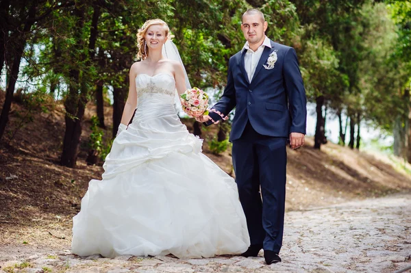 Novia y novio en el día de la boda caminando al aire libre en la naturaleza de primavera. Pareja nupcial, feliz mujer recién casada y hombre abrazándose en el parque verde. Amar pareja de boda al aire libre . —  Fotos de Stock