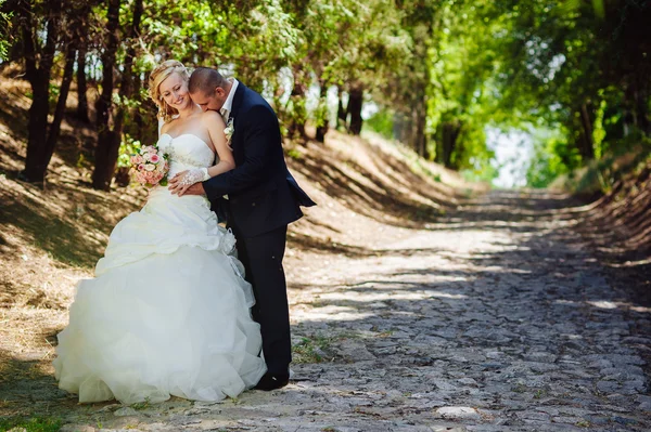 Bruid en bruidegom op huwelijksdag buiten lopen op lente aard. bruidspaar, gelukkig jonggehuwde vrouw en man omarmen in groen park. liefdevolle bruidspaar buiten. — Stockfoto