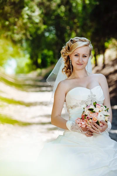 Прекрасная невеста на улице. Невеста держит свадебный букет снаружи. Невеста. Свадебная прическа. Снимок красивой белой невесты на открытом воздухе — стоковое фото