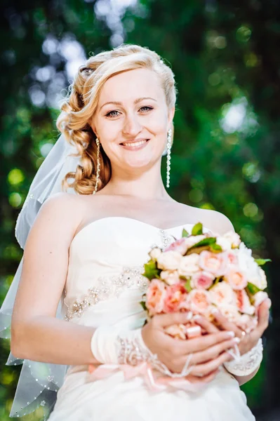 Hermosa novia al aire libre. Novia celebrando el ramo de bodas afuera. Novia. Peinado de boda. Un disparo de una hermosa novia caucásica al aire libre —  Fotos de Stock