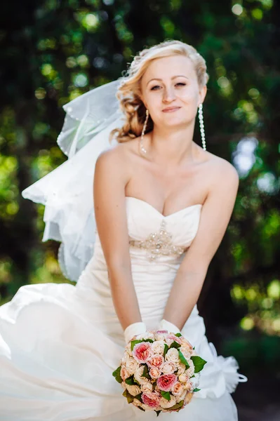 Bela noiva ao ar livre. Noiva segurando buquê de casamento lá fora. Noiva. Penteado de casamento. Um tiro de uma bela noiva branca ao ar livre — Fotografia de Stock