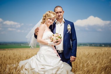 genç güzel düğün çifti çimen bir alana sarılma kulaklı.