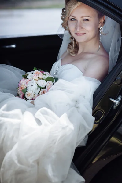 Portret van een mooie bruid in een auto. Close-up portret van een vrij verlegen bruid in een auto-venster. — Stockfoto